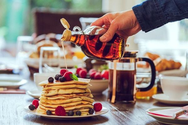 ریختن سیروپ روی پنکیک صبحانه