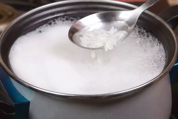 برنج در حال جوشیدن در قابلمه برای تهیه ته چین اسفناج و مرغ