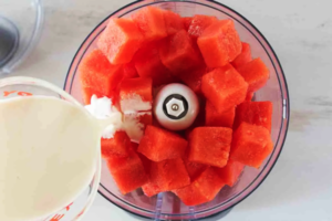 اضافه کردن شیر به تکه های هندوانه در مخلوط کن برای تهیه میلک شیک هندوانه