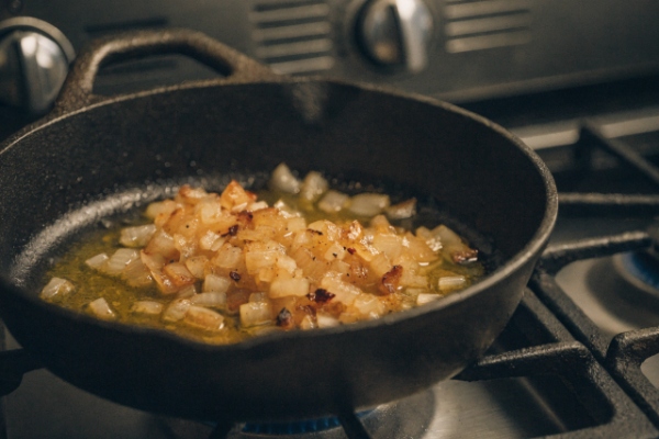 تفت دادن و کاراملی کردن پیاز برای تهیه پاستا با ماست و پیاز