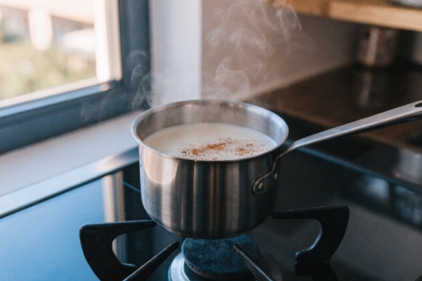 گرم کردن شیر و خامه با ادویه‌ها برای تهیه اگ ناگ