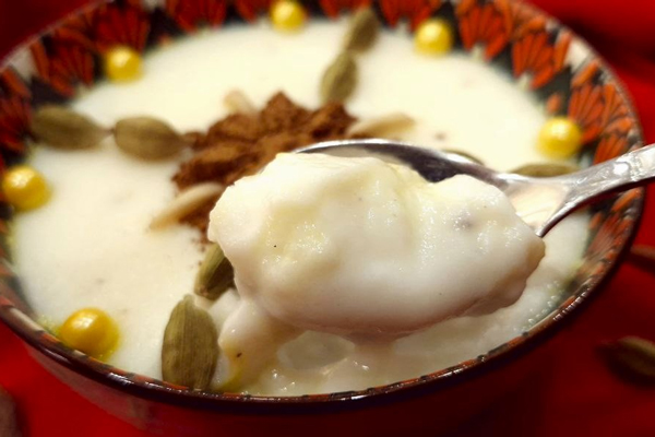 یک کاسه فرنی با نشاسته و آب با تزئین هل و گردو