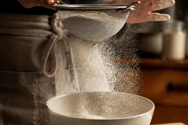 مخلوط کردن مواد خشک در تهیه کلوچه کنجدی