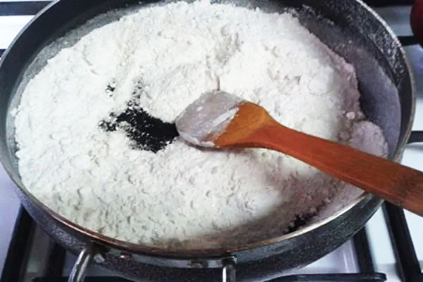 خنک کردن آرد برای تهیه حلوای زعفرانی با شیرخشک