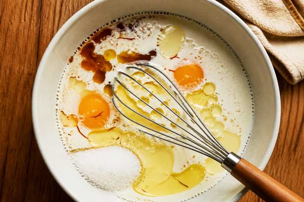 مخلوط کردن روغن، شیر، زعفران در تهیه شیرینی دانمارکی با آرد گندم