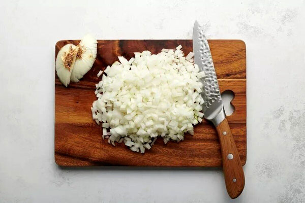 پیاز خرد شده روی تخته با چاقو برای تهیه نرگسی با رب انار