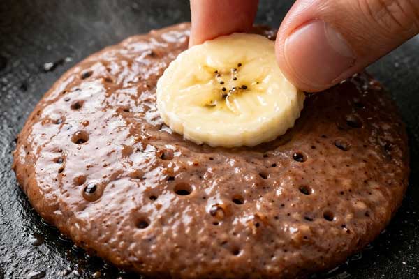 ریختن ملایه پنکیک شکلاتی و گذاشتن حلقه موز روی آن
