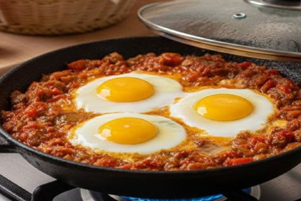 افزودن تخم مرغ به میرزا قاسمی در تابه 