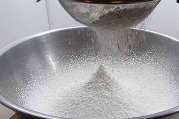 الک کردن آرد سفید برای تهیه شیرینی نارگیلی با آرد سفید