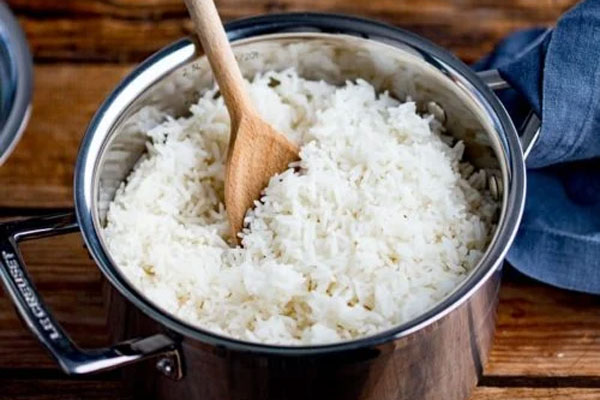 مخلوط کردن برنج با کفگیر چوبی 