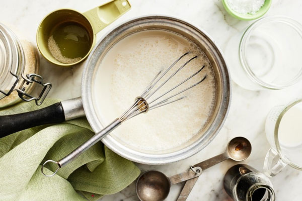 مایه غلیظ شده بستنی در قابلمه با همزن دستی برای تهیه بستنی پروبیوتیک 