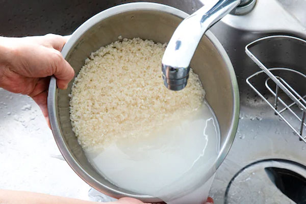 شستن برنج برای تهیه برنج زعفرانی با روغن حیوانی
