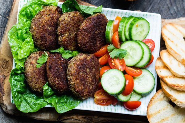 سرو کتلت کینوا در کنار گوجه و خیار و کاهو