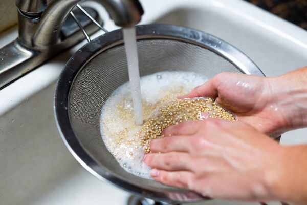 شستن کینوا به وسیله صافی برای تهیه کتلت کینوا