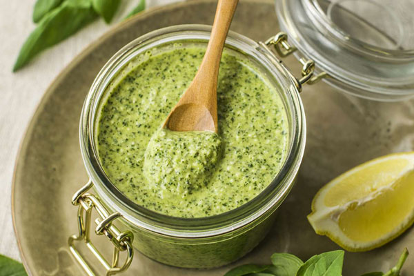 سس پستو در ظرف شیشه ای با قاشق چوبی برای تهیه بروسکتای چیاتلا و آووکادو