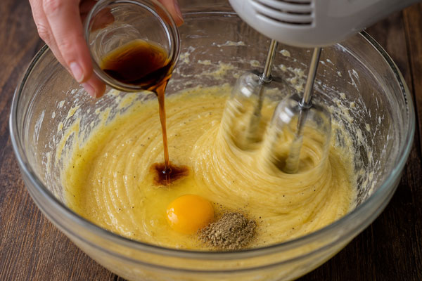 اضافه کردن تخم‌مرغ، وانل مایع و هل به مخلوط روغن در تهیه شیرینی شکری کرمانشاه