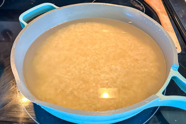 جوشاندن برنج پخته برای تهیه ته چین مرغ با گرد غوره