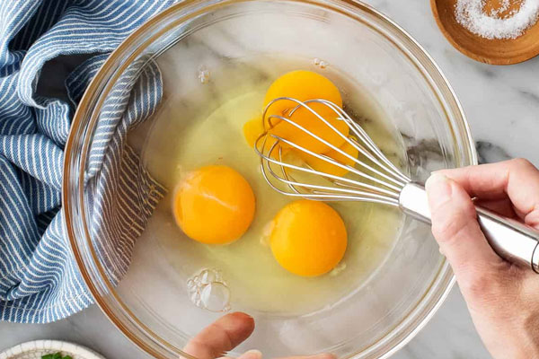 مخلوط کردن تخم مرغ برای پخت اشکنه کشک 