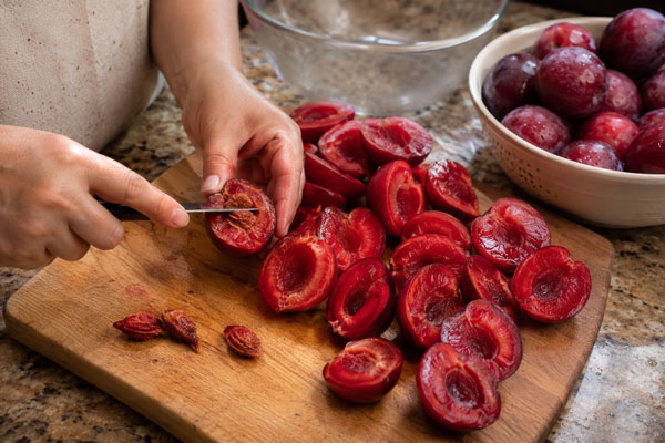 خرد و آماده کردن آلوها برای تهیه لواشک روی گاز