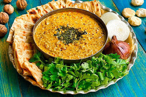 سرو اشکنه کشک همراه با نان تازه، پیاز و سبزی 