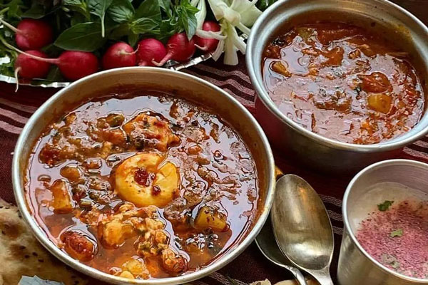 سرو اشکنه گوجه در ظرف استیل با سبزی خوردن 