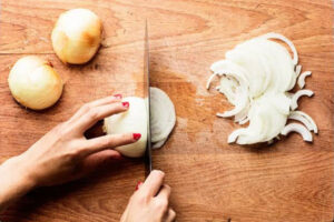 خلالی کردن پیاز با چاقو روی تخته برای تهیه جغور بغور دل مرغ