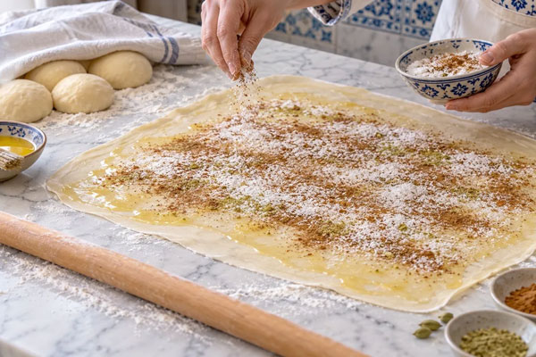 اضافه کردن پودر قند هل و دارچین روی خمیر یوخه 